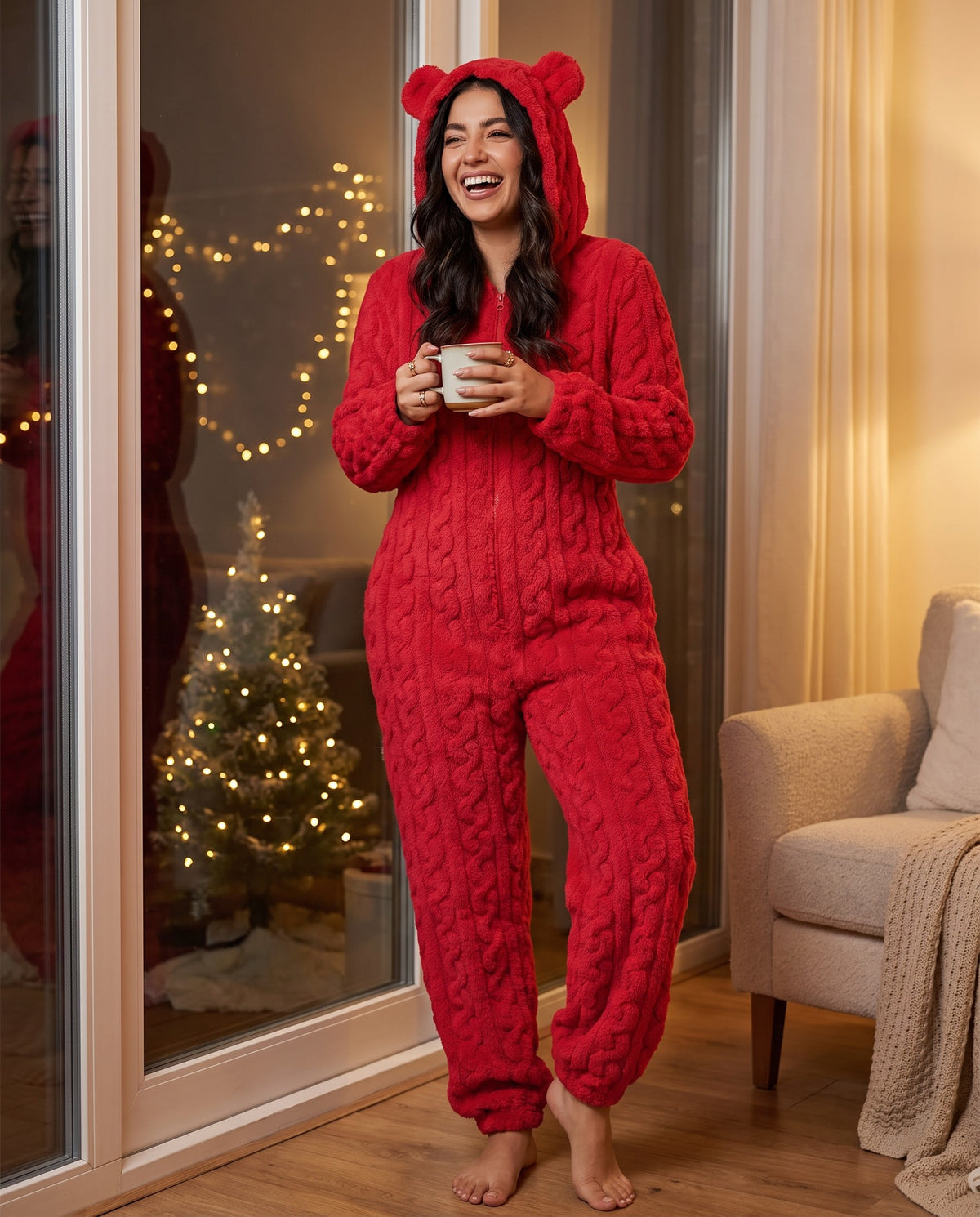 Woman laughing with a mug by the window in the TEDDY Cozy Bear Onesie in Red, hood up with bear ears